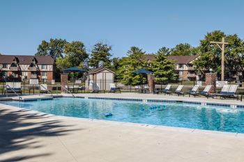 a swimming pool with chairs and umbrellas at Bavarian Village Apartments, Indiana, 46235